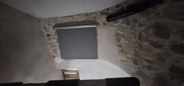 Pedra, reboco e uma janela com estore.